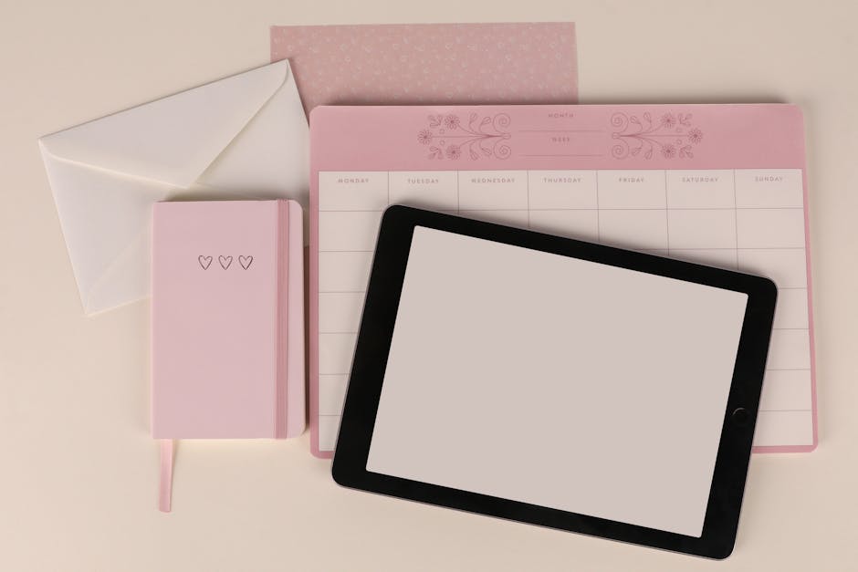 Flat lay of a pink planner, envelope, and tablet on a desk, perfect for organization themes.